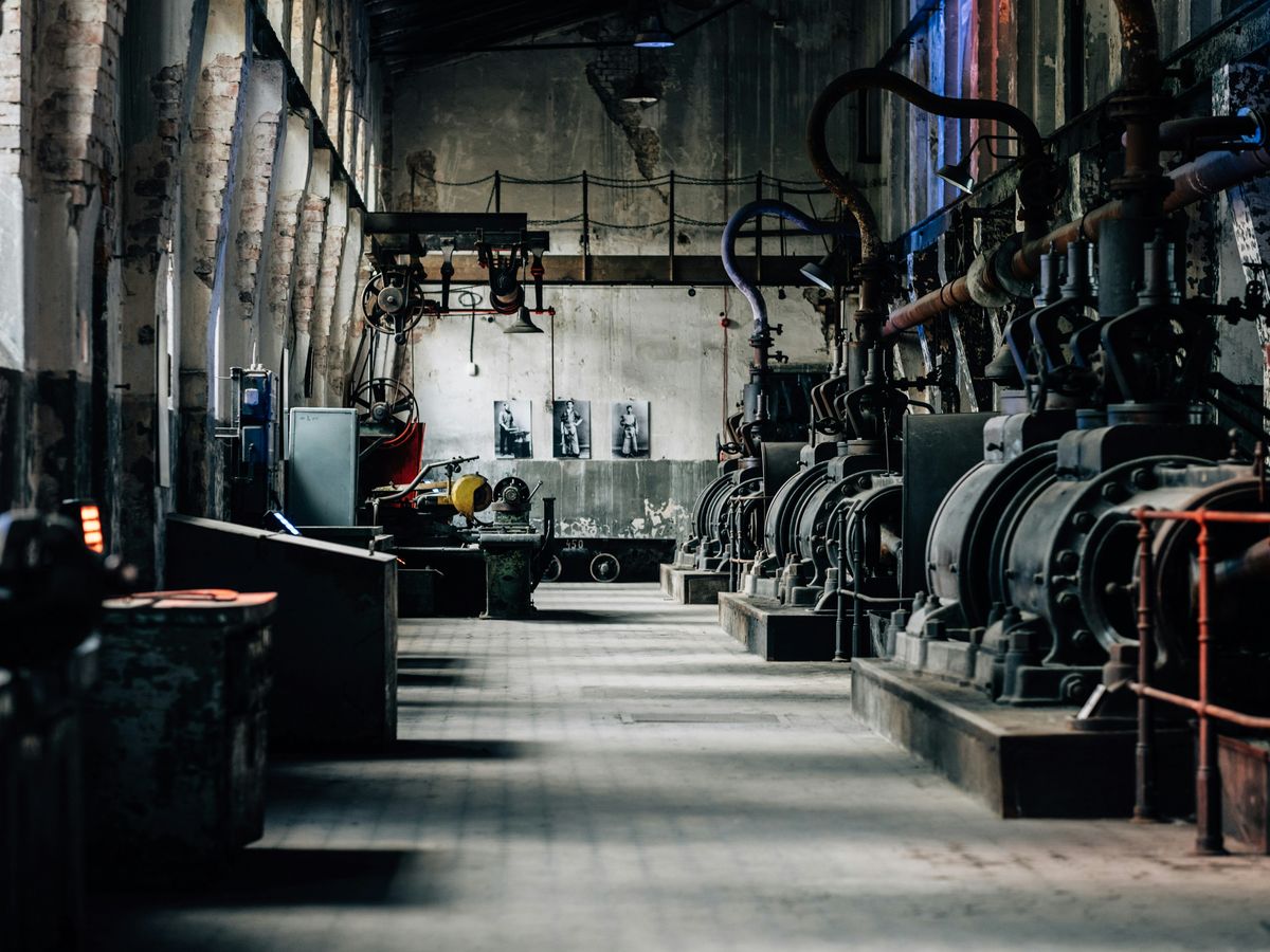 Historisch machinepark met hydraulische persen en archieffoto's van medewerkers aan de muur